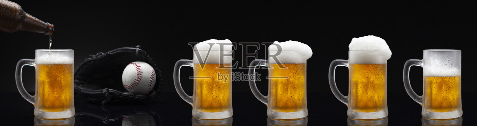 棒球加冰五杯啤酒，上面满是水珠——凝结。站在黑色背景的黑色桌子上照片摄影图片