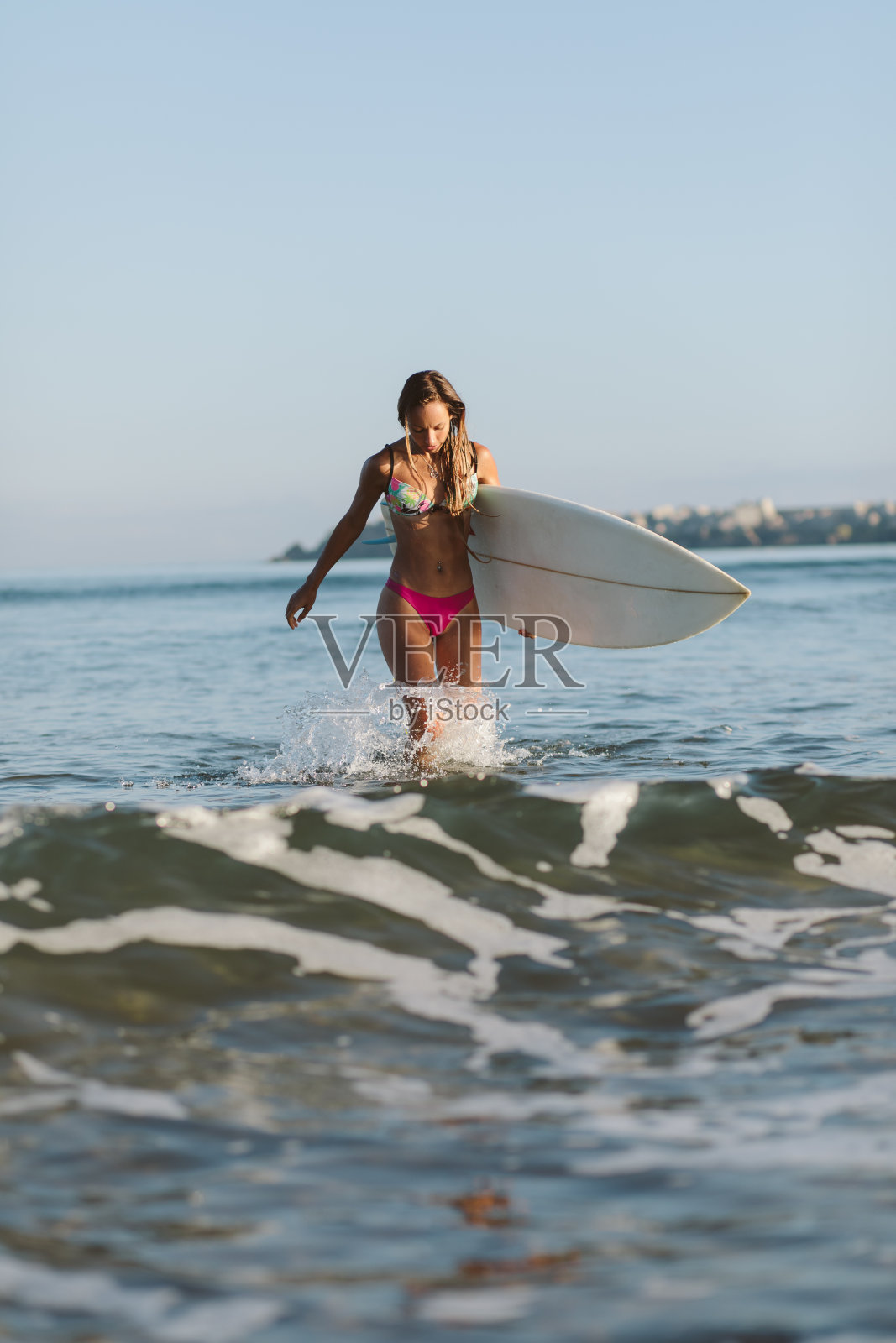 漂亮的冲浪运动员在海里用她的冲浪板冲浪照片摄影图片