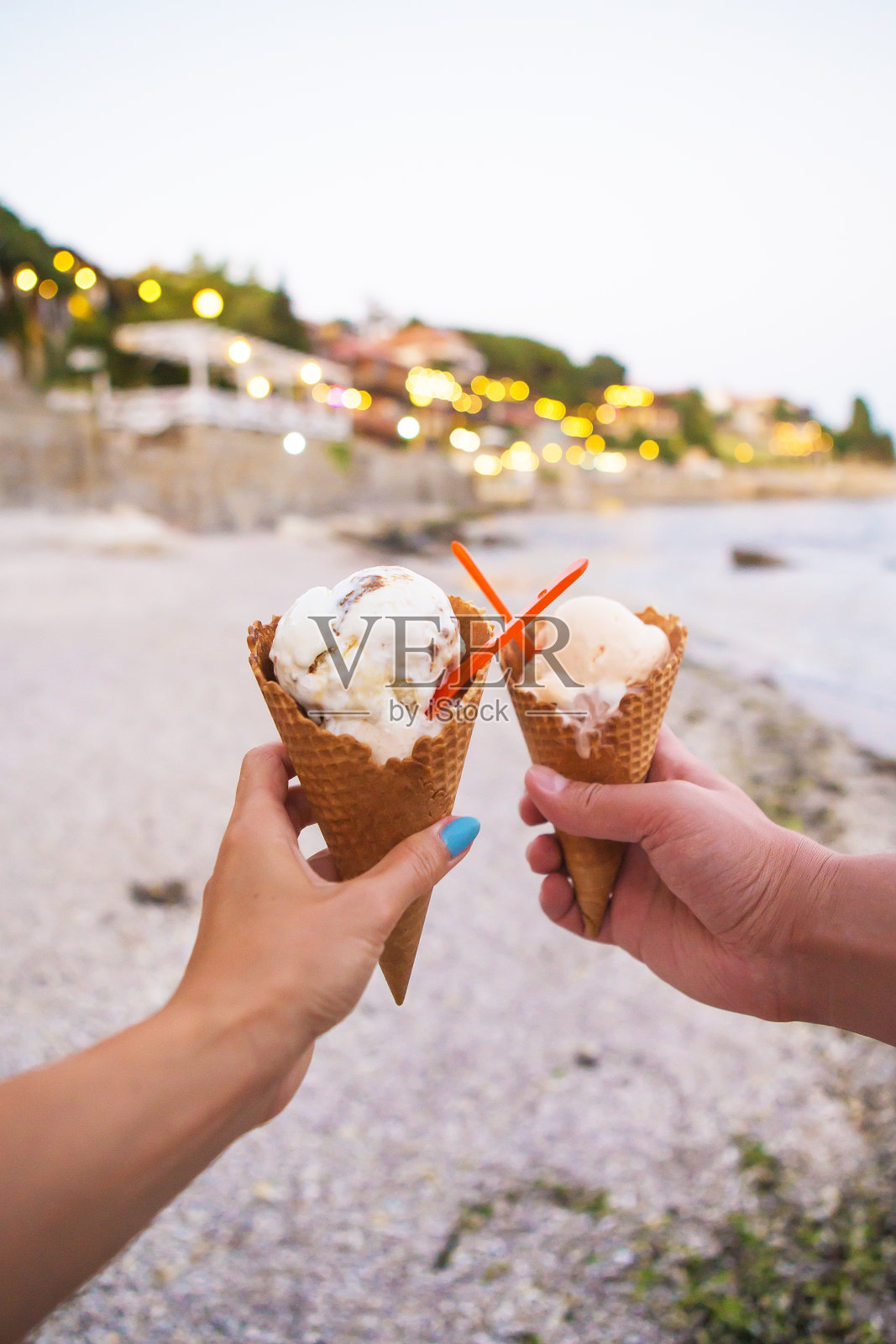 夏日沙滩上，两只手捧着美味的冰淇淋，特写镜头照片摄影图片