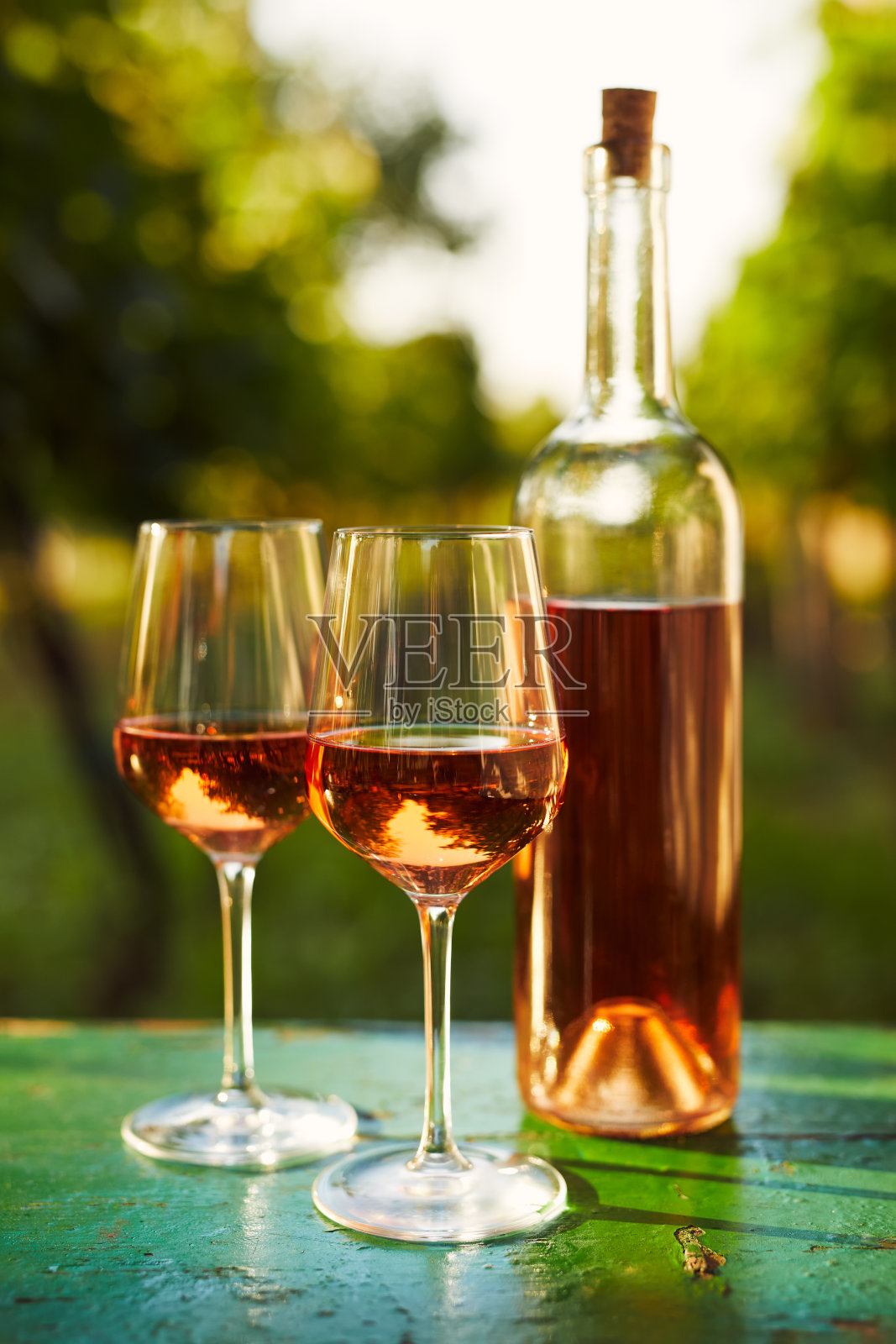 两个玻璃杯和一瓶rosÃ©葡萄酒放在一张旧木桌上照片摄影图片
