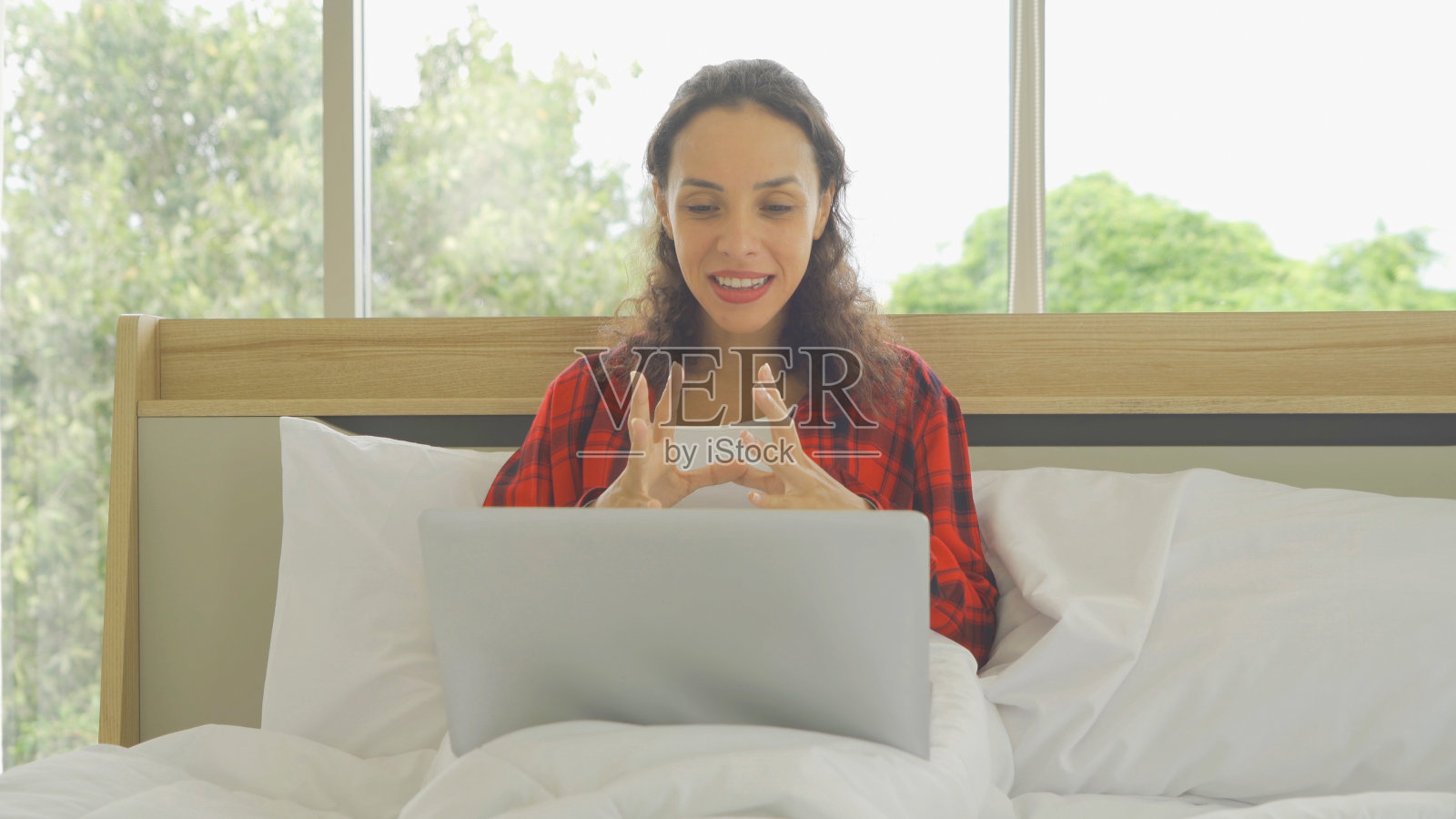 快乐微笑的商业，拉丁妇女，人们在网络摄像头视频会议与电脑笔记本电脑设备，电话会议，在隔离在床上工作在卧室在家里。的生活方式。照片摄影图片