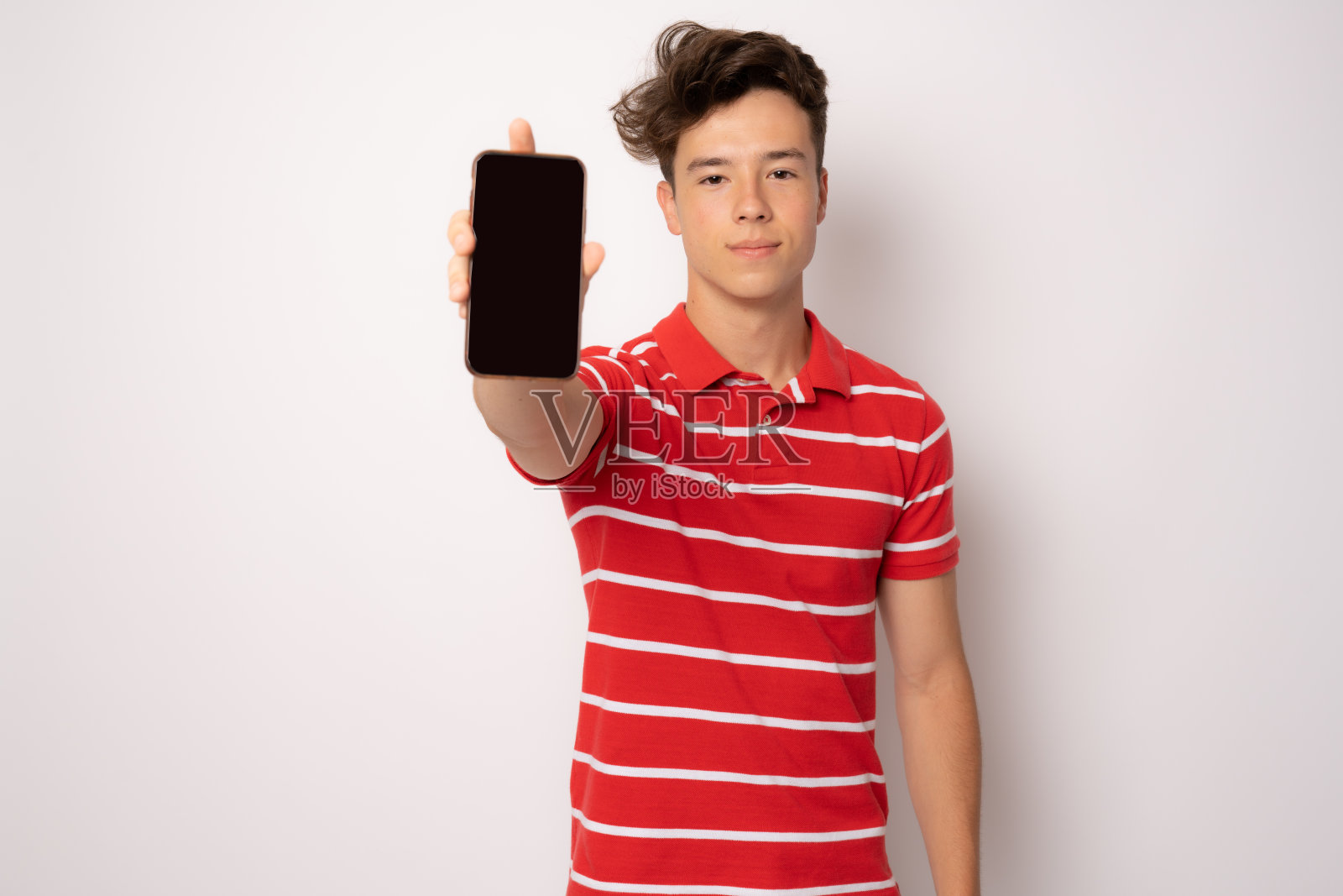 一个开朗的年轻人的肖像穿着休闲服孤立在白色背景下，显示黑屏手机照片摄影图片