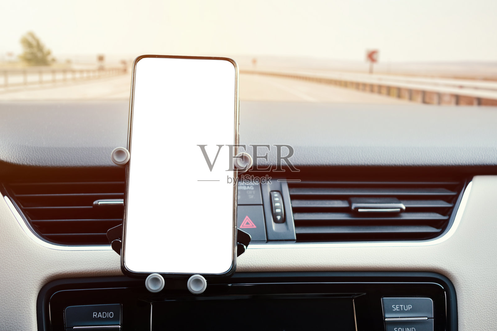 安装在车内通风格栅上的手机架，以及一部手机的白屏照片摄影图片