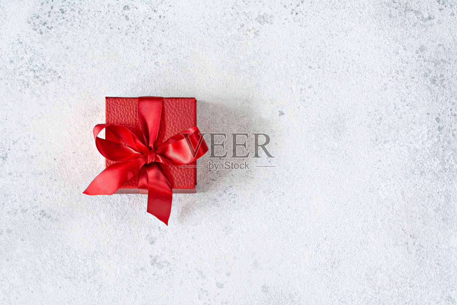 红色礼品盒与红色缎带(蝴蝶结)在一个浅色的背景。祝贺情人节，圣诞节，新年，生日照片摄影图片