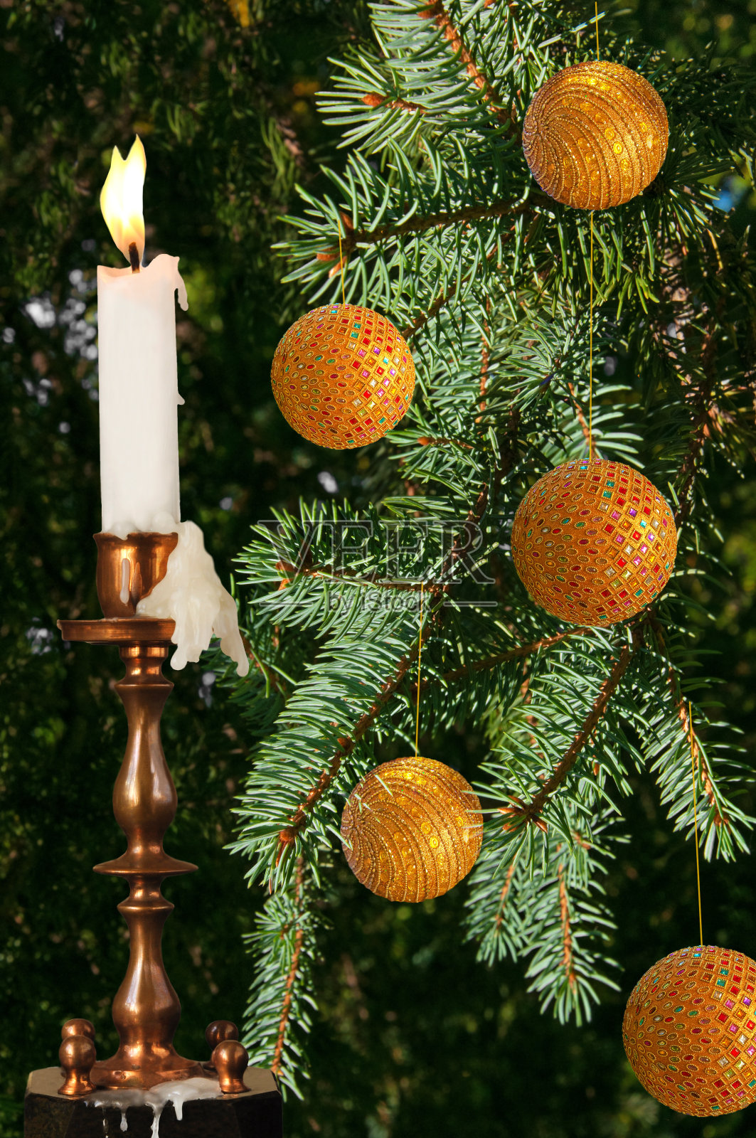 黄色的圣诞球放在绿色的冷杉树枝上，旧烛台上有一支燃烧的蜡烛照片摄影图片
