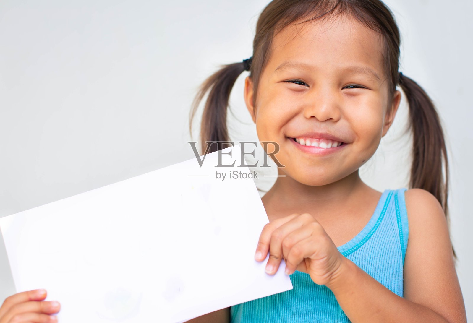 一个快乐的小女孩的肖像，拿着一个空白的白色标志。的孩子。照片摄影图片