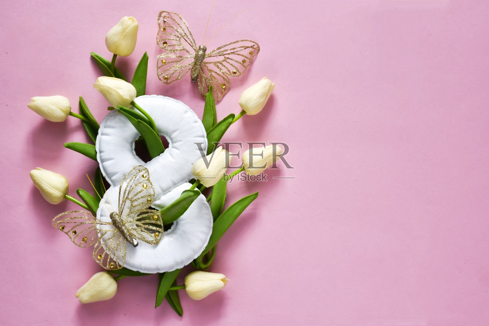 三八国际妇女节贺卡。白色郁金香，蝴蝶和白色数字8在粉红色的背景。复制空间，平铺。节日的概念照片摄影图片
